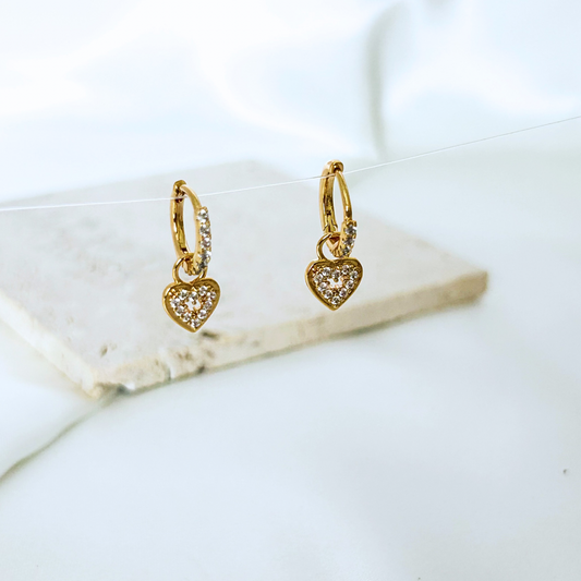 Gold heart-shaped earrings on a marble surface