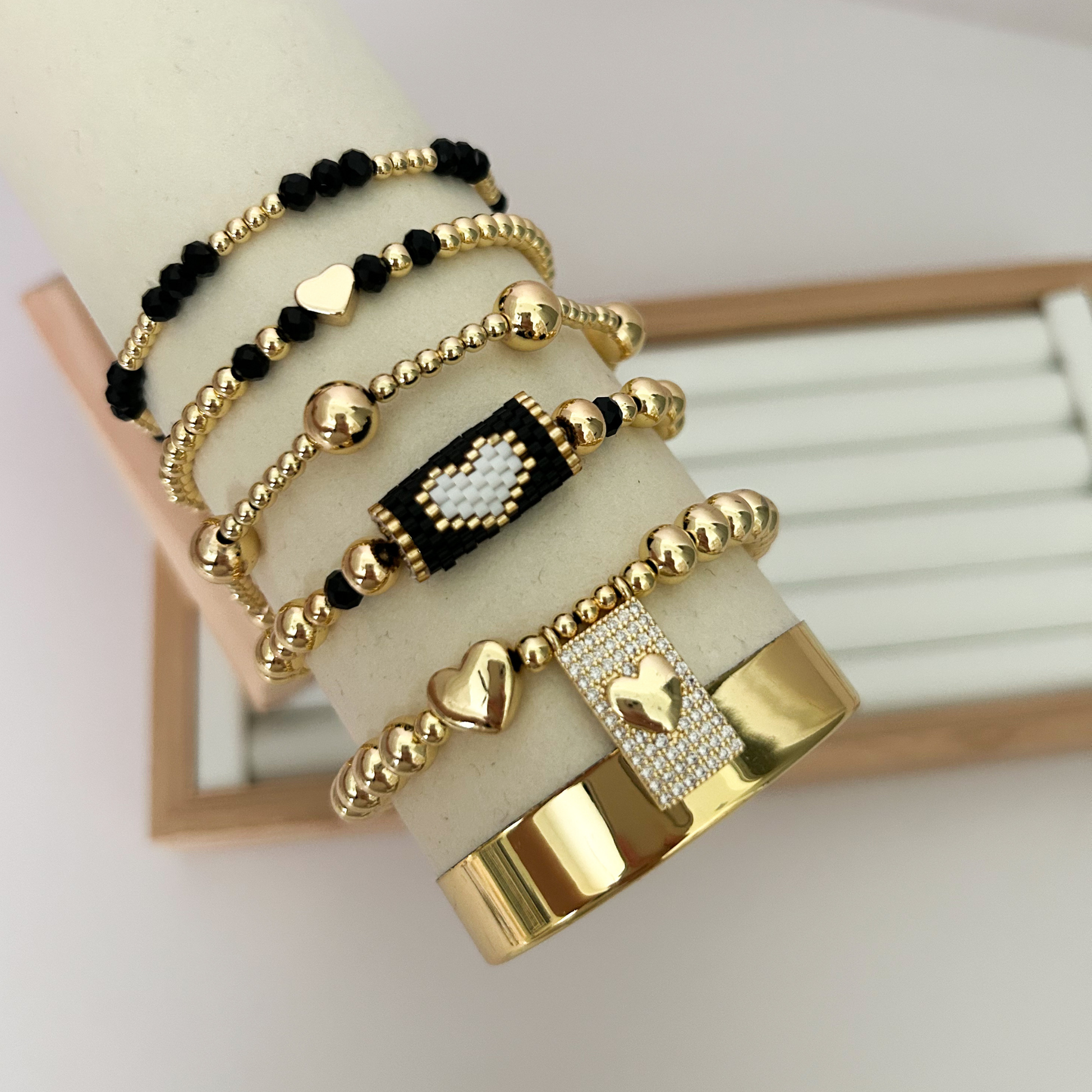 Black gold heart bracelet set with pavé charm displayed on jewelry stand