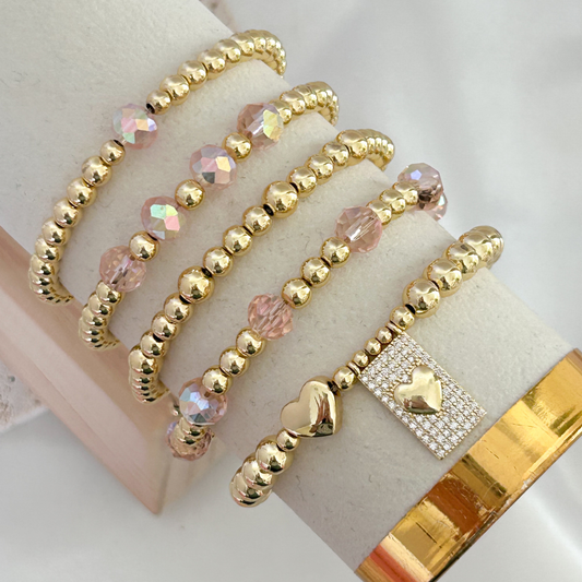 Gold beaded bracelet with pink beads on a white surface