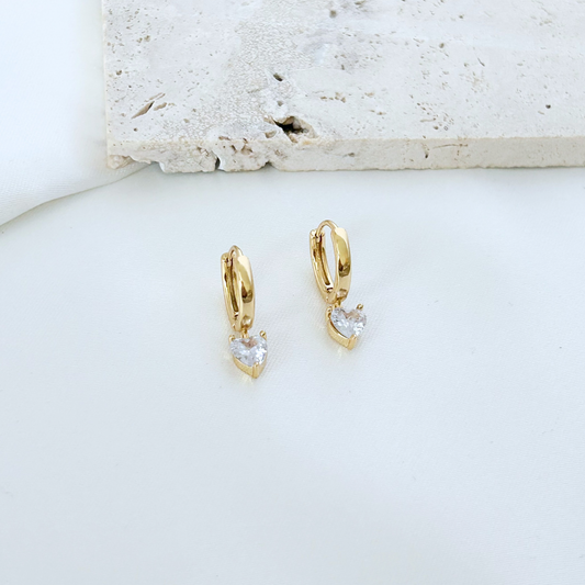 Gold hoop earrings with clear stones on a light background