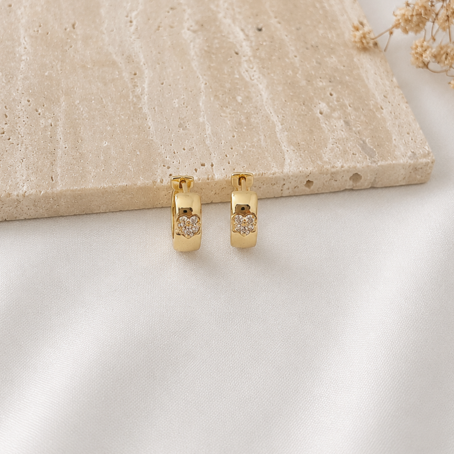Pair of polished gold-tone huggie hoop earrings featuring a sparkling pavé heart set into the front of each hoop. Elegant minimalist earrings with a timeless heart design, perfect for everyday wear, gifting, or layering with other gold jewelry.