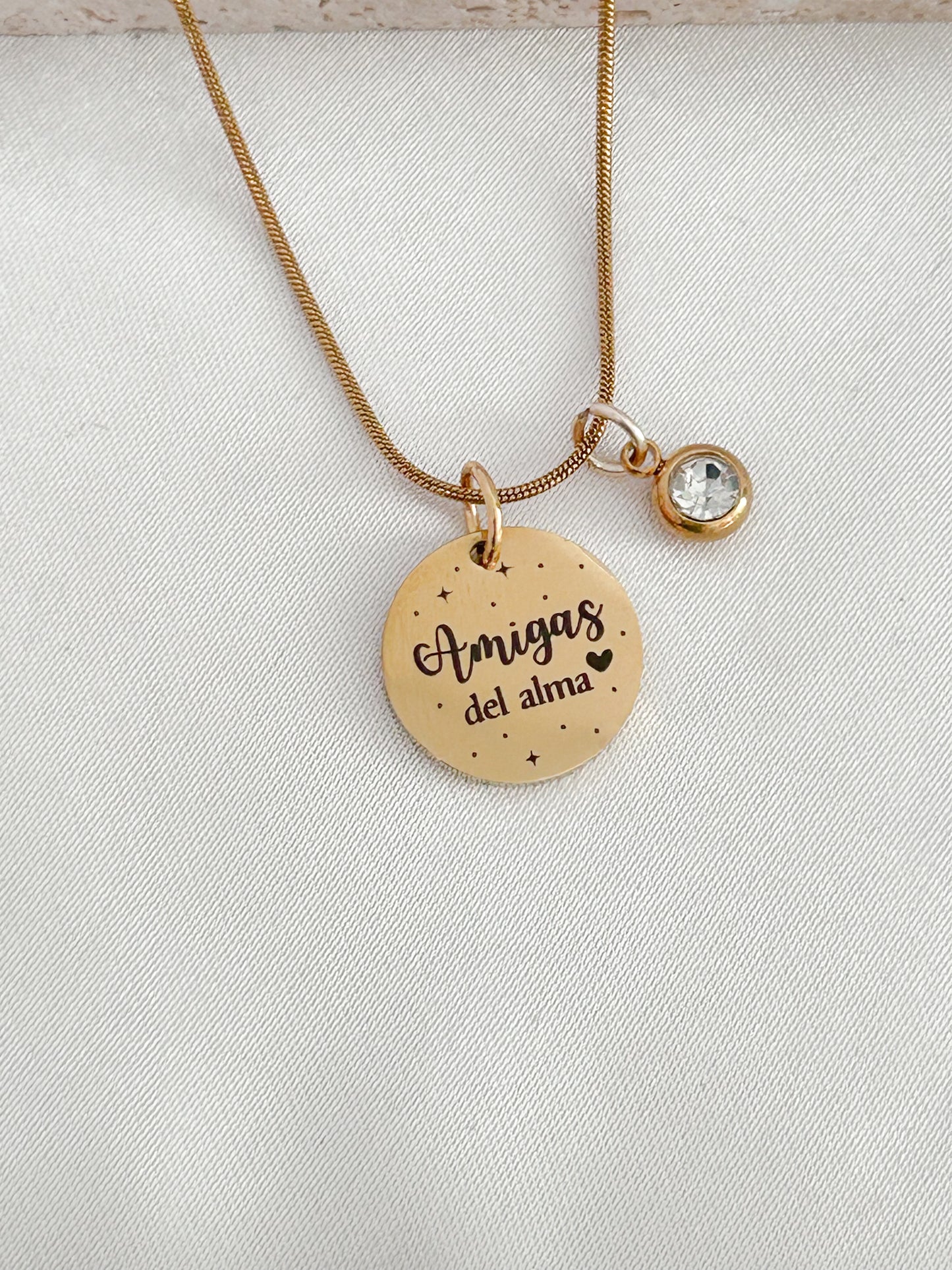 Gold necklace with a round pendant and a smaller round charm on a light gray background