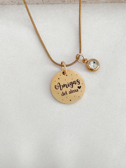 Gold necklace with a round pendant and a smaller round charm on a light gray background