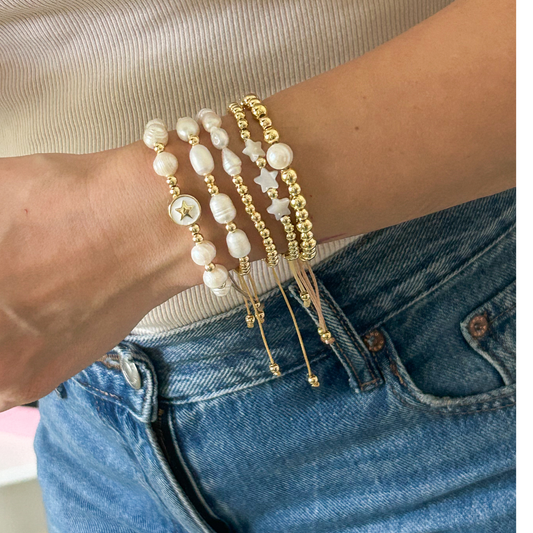 Gold beaded bracelet stack with baroque pearls and mother of pearl stars on wrist
