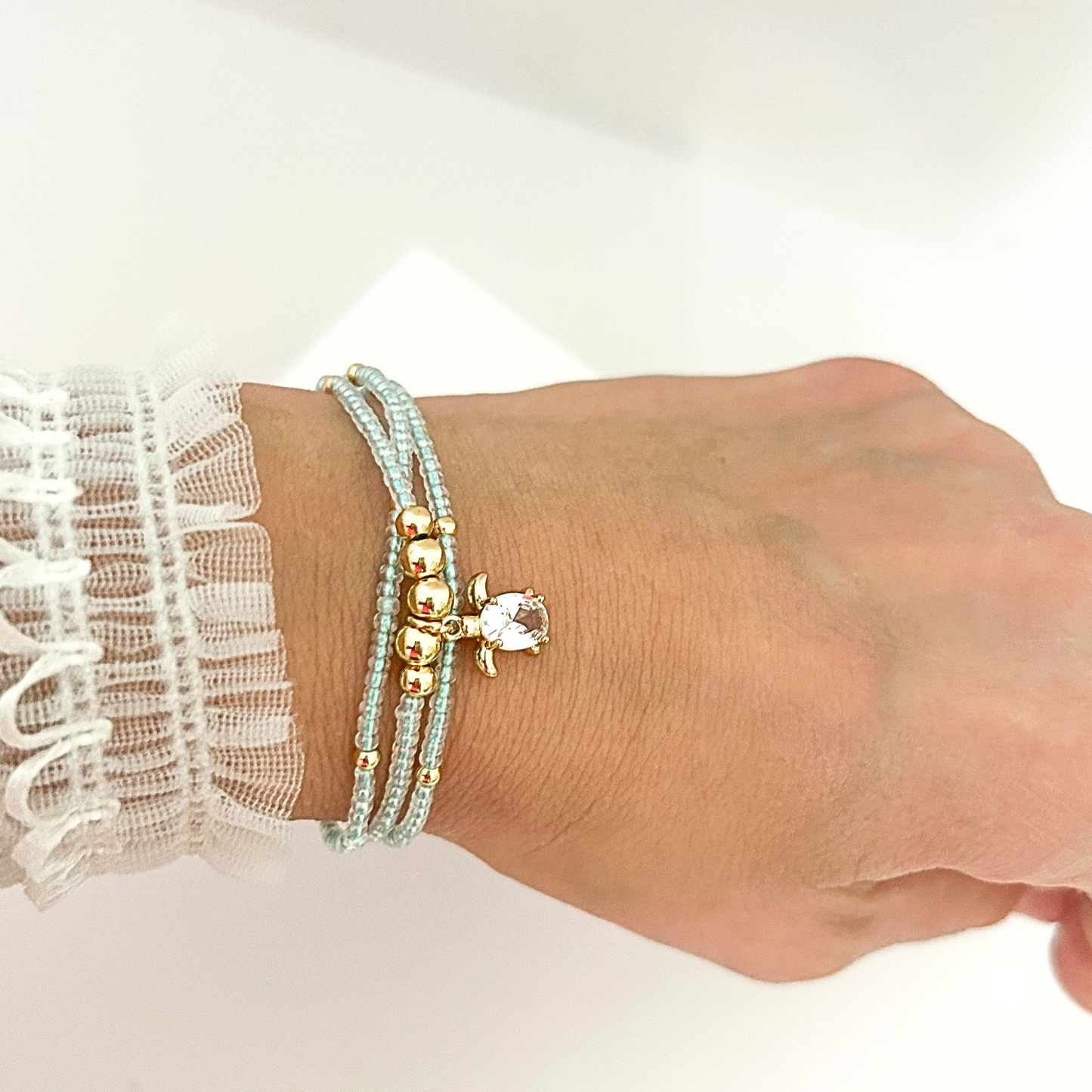 Lightweight adjustable bracelet with multiple strands of aqua seed beads, gold-tone details, and a shimmering turtle charm.