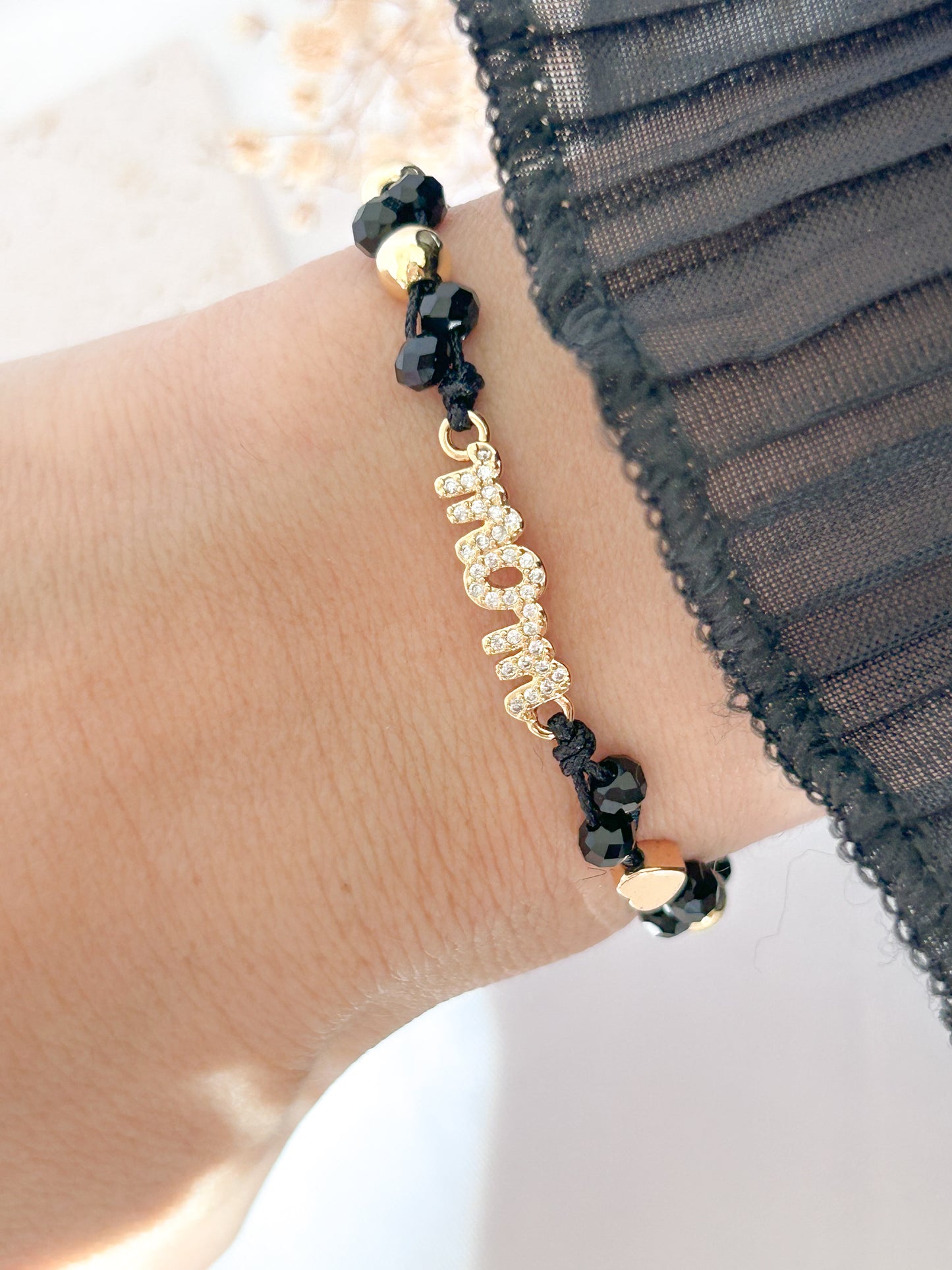 Bracelet with black beads and gold chain on a wrist