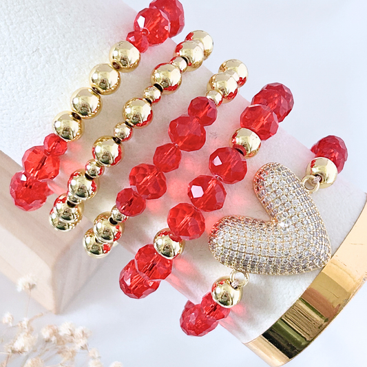 Red and gold beaded necklace with a heart-shaped pendant on a white surface