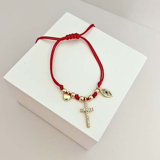 Adjustable red string bracelet featuring a crystal cross charm, evil eye detail, and gold-tone accents.