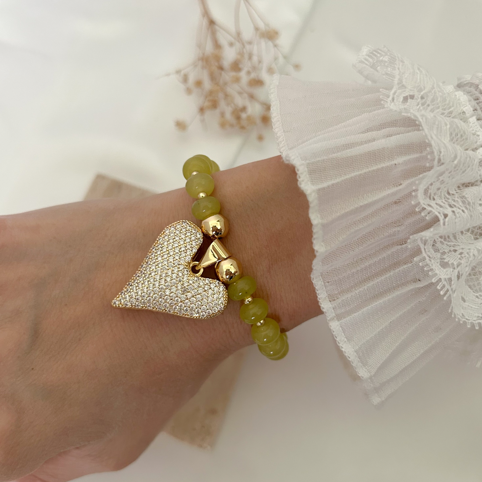 Chic heart charm bracelet available in olive green beads, accented with gold-tone details and a dazzling crystal-covered heart centerpiece.