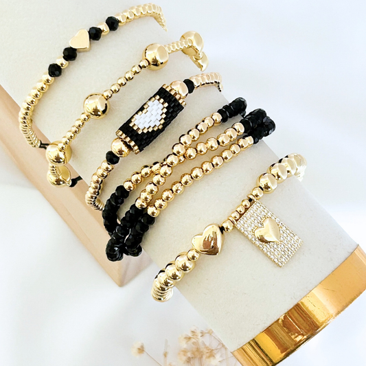 Set of gold and black beaded bracelets on a white surface