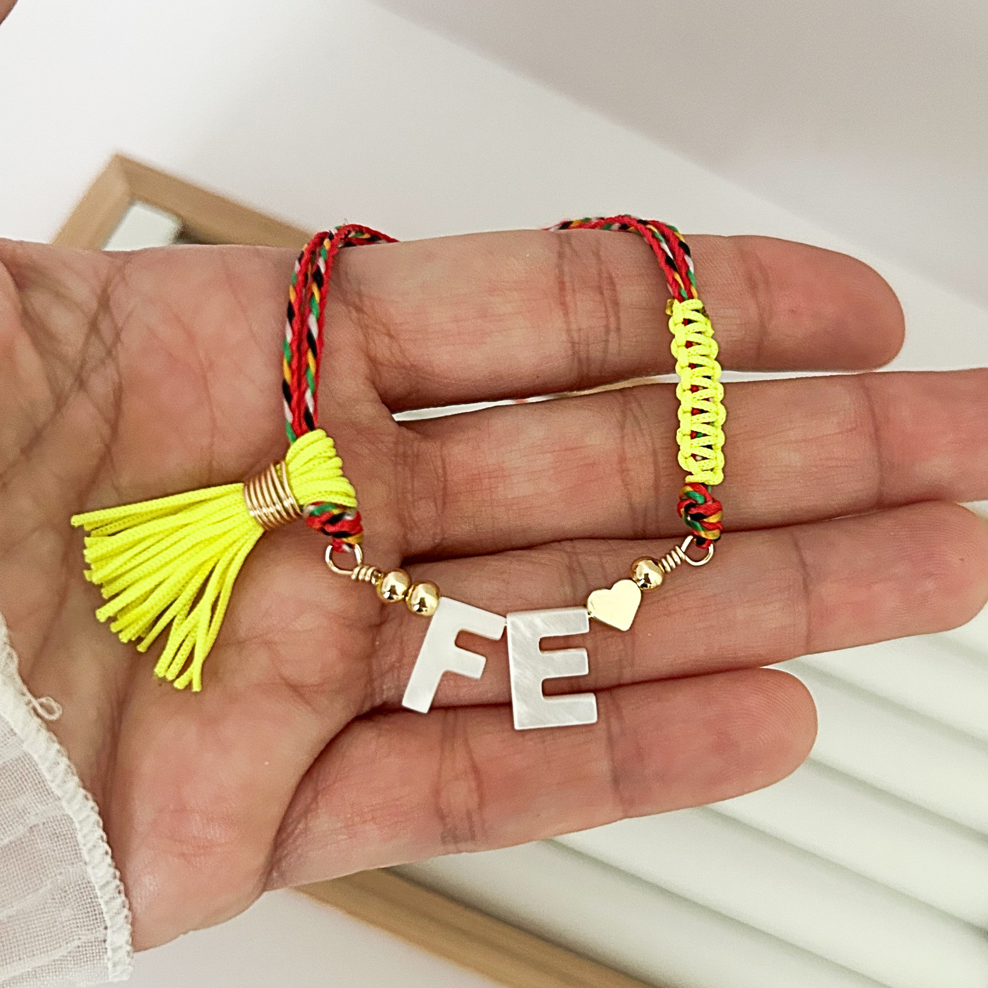 Adjustable multicolor cord faith bracelet with neon yellow tassel and white Fe letter gold charm on jewelry on hand 