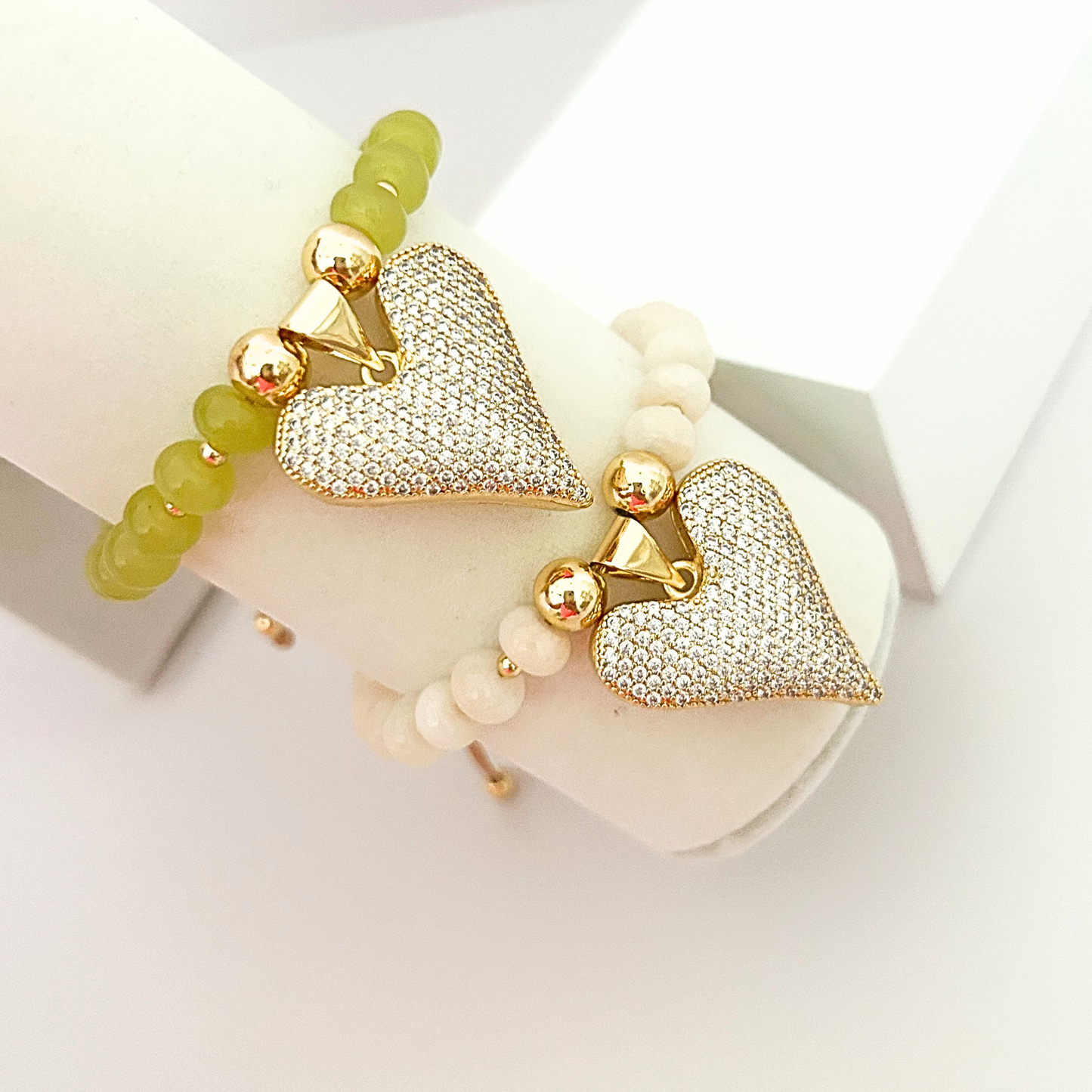 Set of adjustable beaded bracelets featuring sparkling crystal heart pendants, gold-tone accents, and soft olive green and ivory beads.