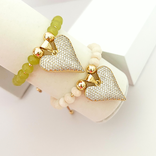 Set of adjustable beaded bracelets featuring sparkling crystal heart pendants, gold-tone accents, and soft olive green and ivory beads.