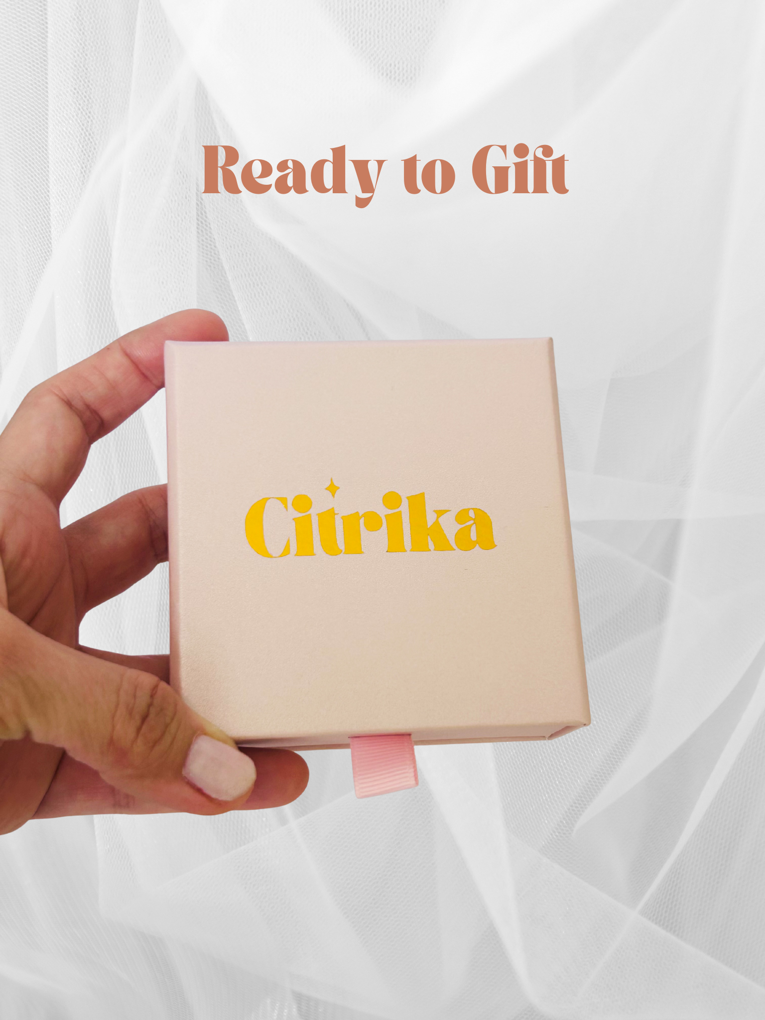 Hand holding a beige box with 'Citrika' branding against a white background